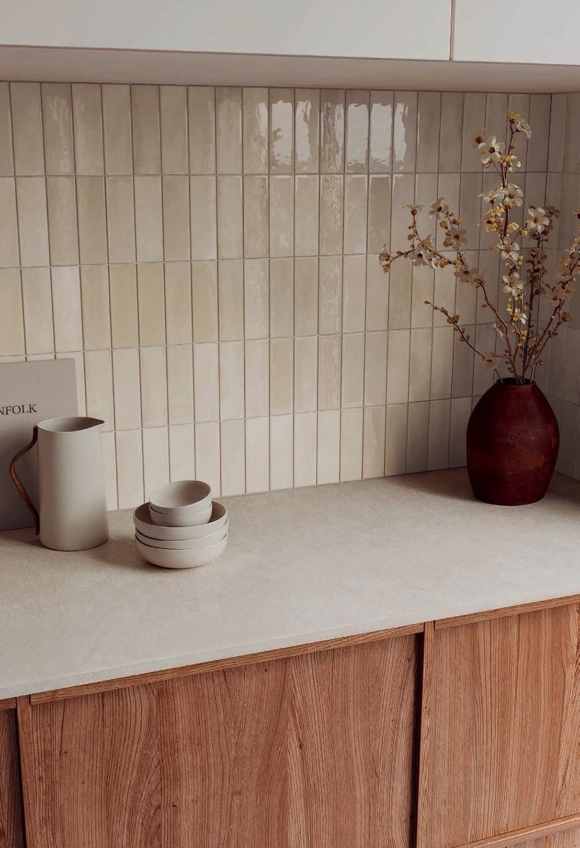 Arrangement of several Calema 2x6 Greige Gloss ceramic wall tiles, highlighting the subtle color variation and reflective surface.