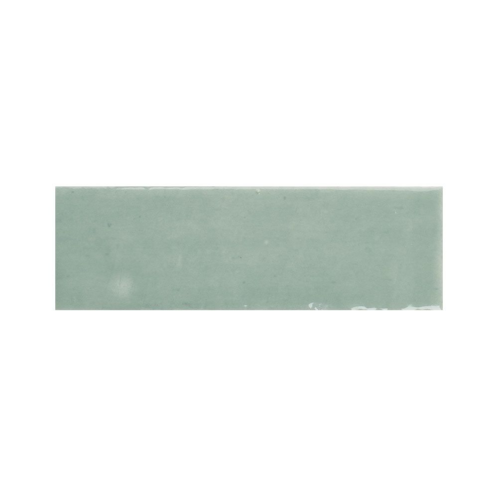 Arrangement of multiple 2x5 inch kiwi green gloss ceramic tiles showing color variation
