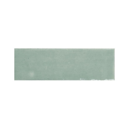 Arrangement of multiple 2x5 inch kiwi green gloss ceramic tiles showing color variation